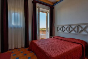 Quarto de hotel com cama, janela com cortinas e vista para o exterior.