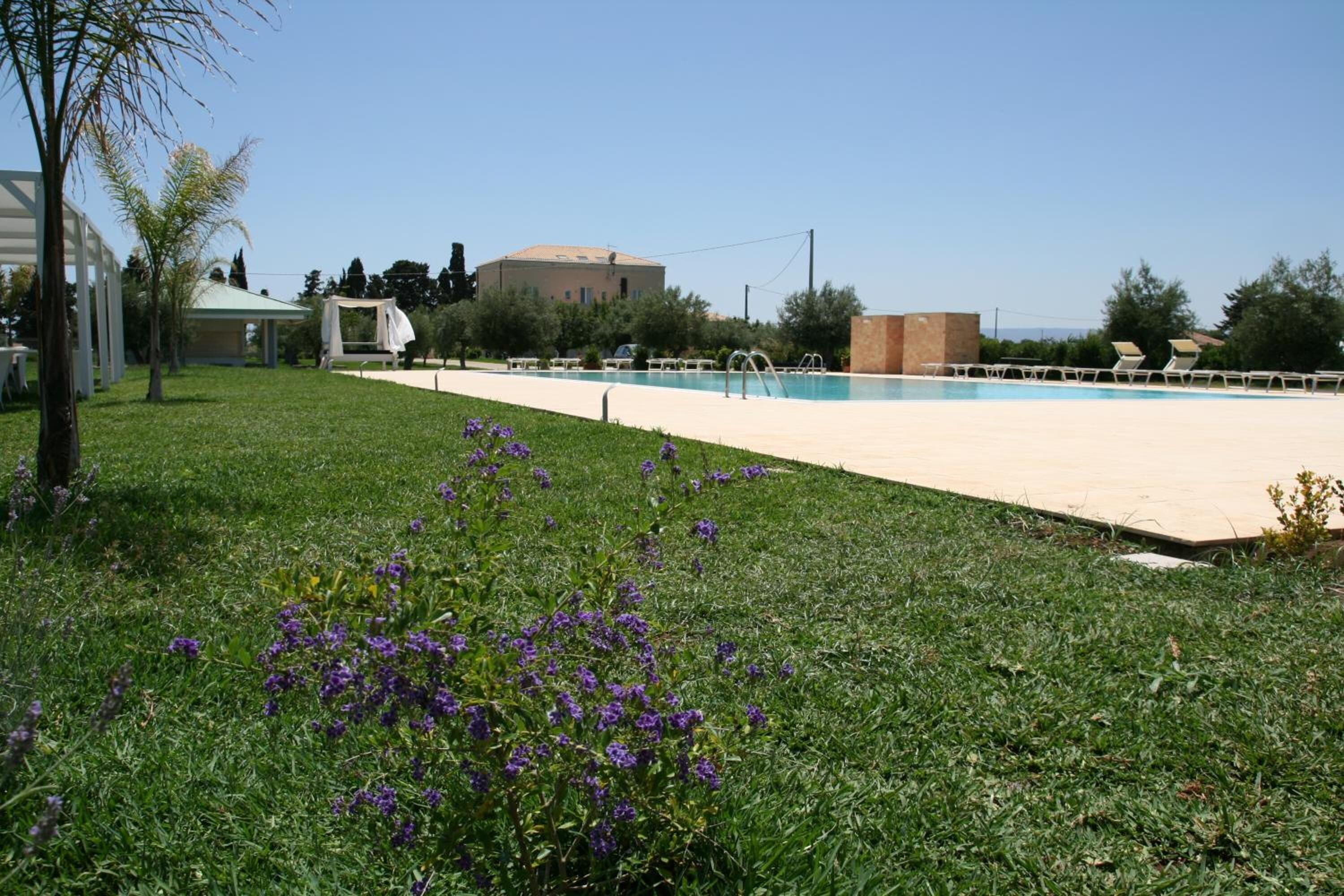Una piscina amb una vista clara de l'entorn, incloent-hi un prat verd i un edifici al fons.