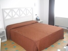 A bedroom with a bed, a bedside table, a telephone, and a radiator.
