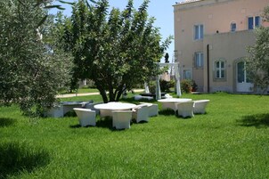 A grassy outdoor area with white furniture and a building in the background.
