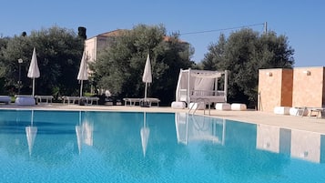 Una piscina al aire libre de temporada, sombrillas, tumbonas