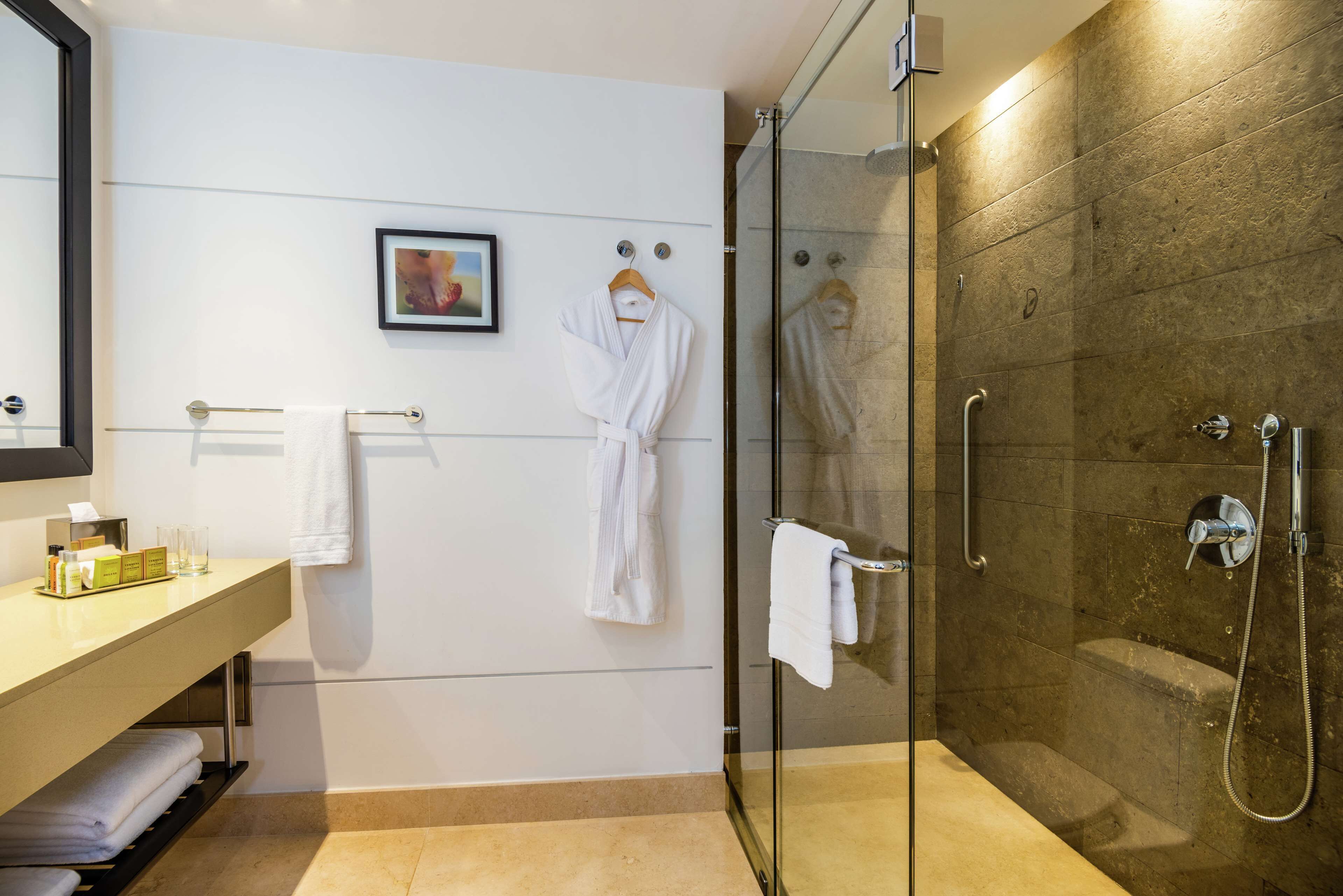 A modern bathroom with a glass shower enclosure, a vanity with a towel rack, and a framed picture on the wall.