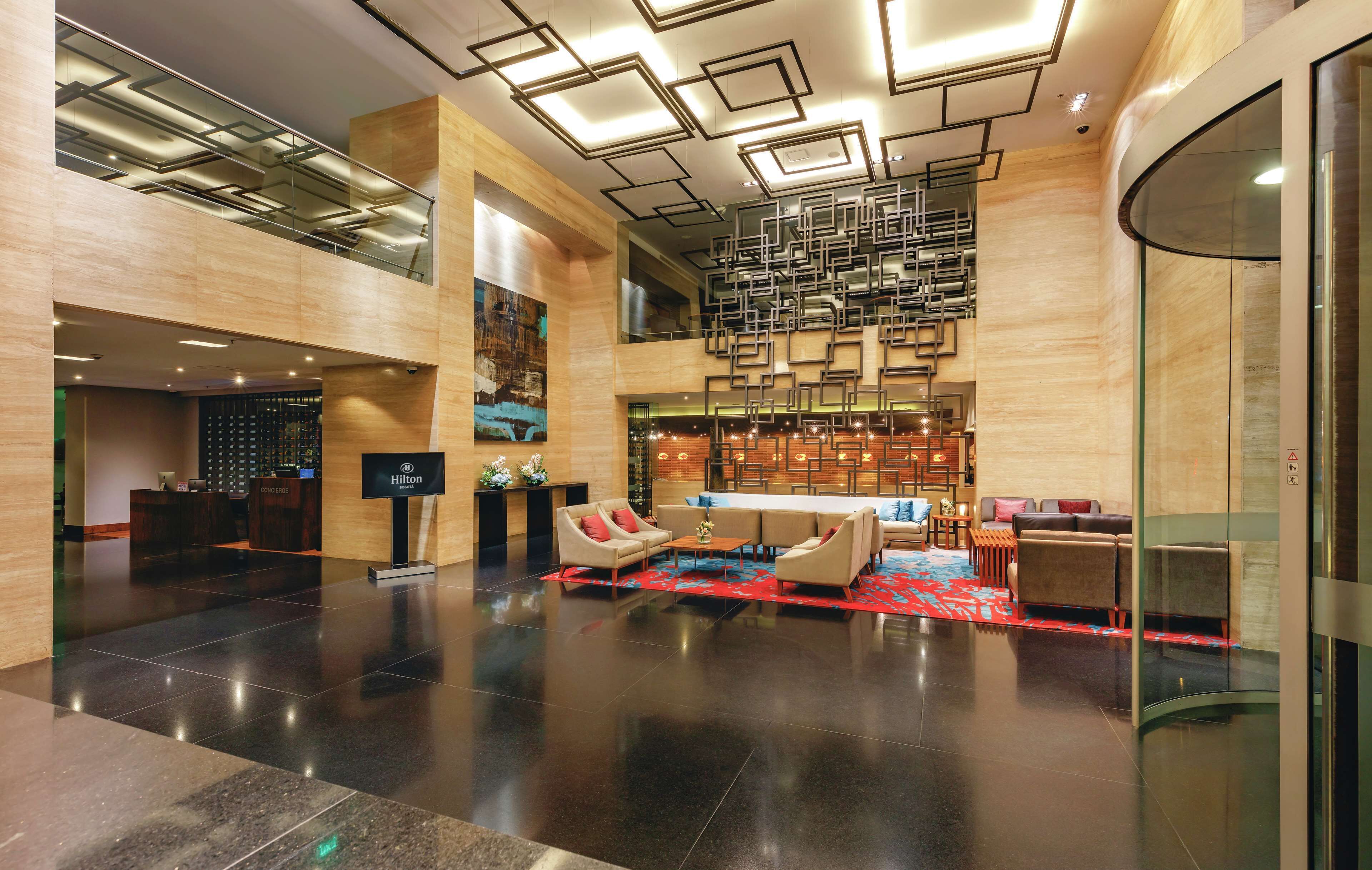 Un moderno vestíbulo de hotel con recepción, zona de estar y bar.