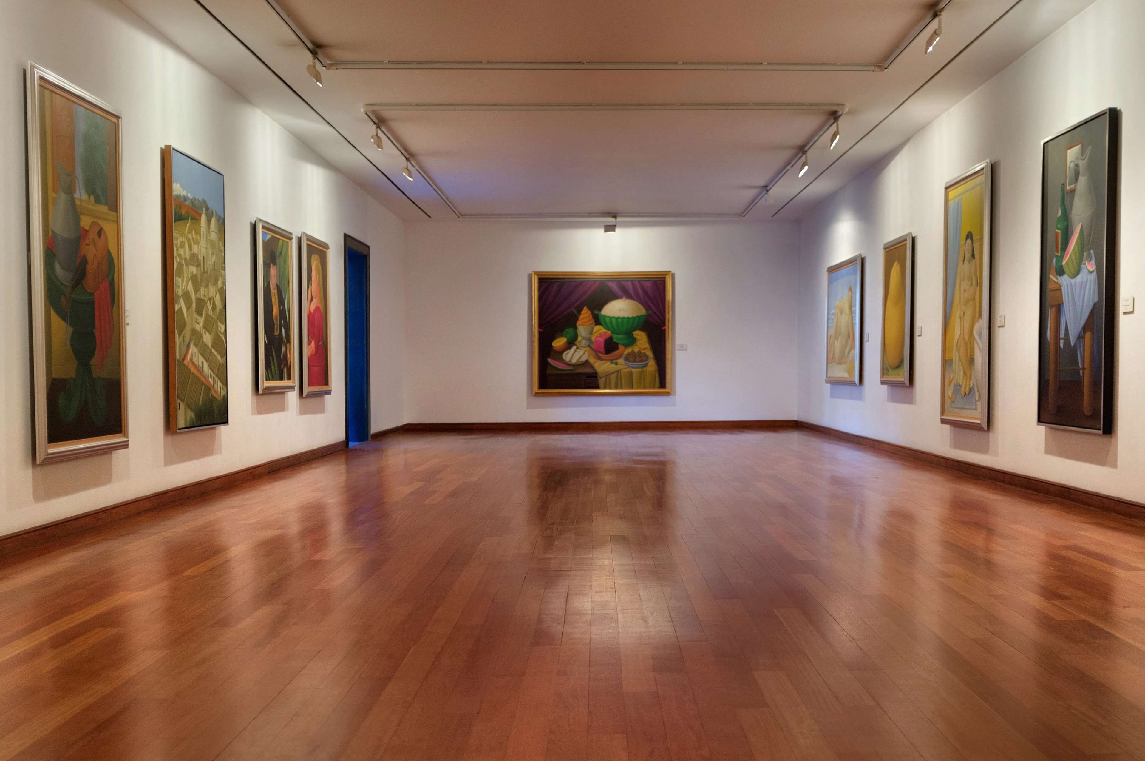 Uma galeria de arte com piso de madeira e quadros nas paredes.