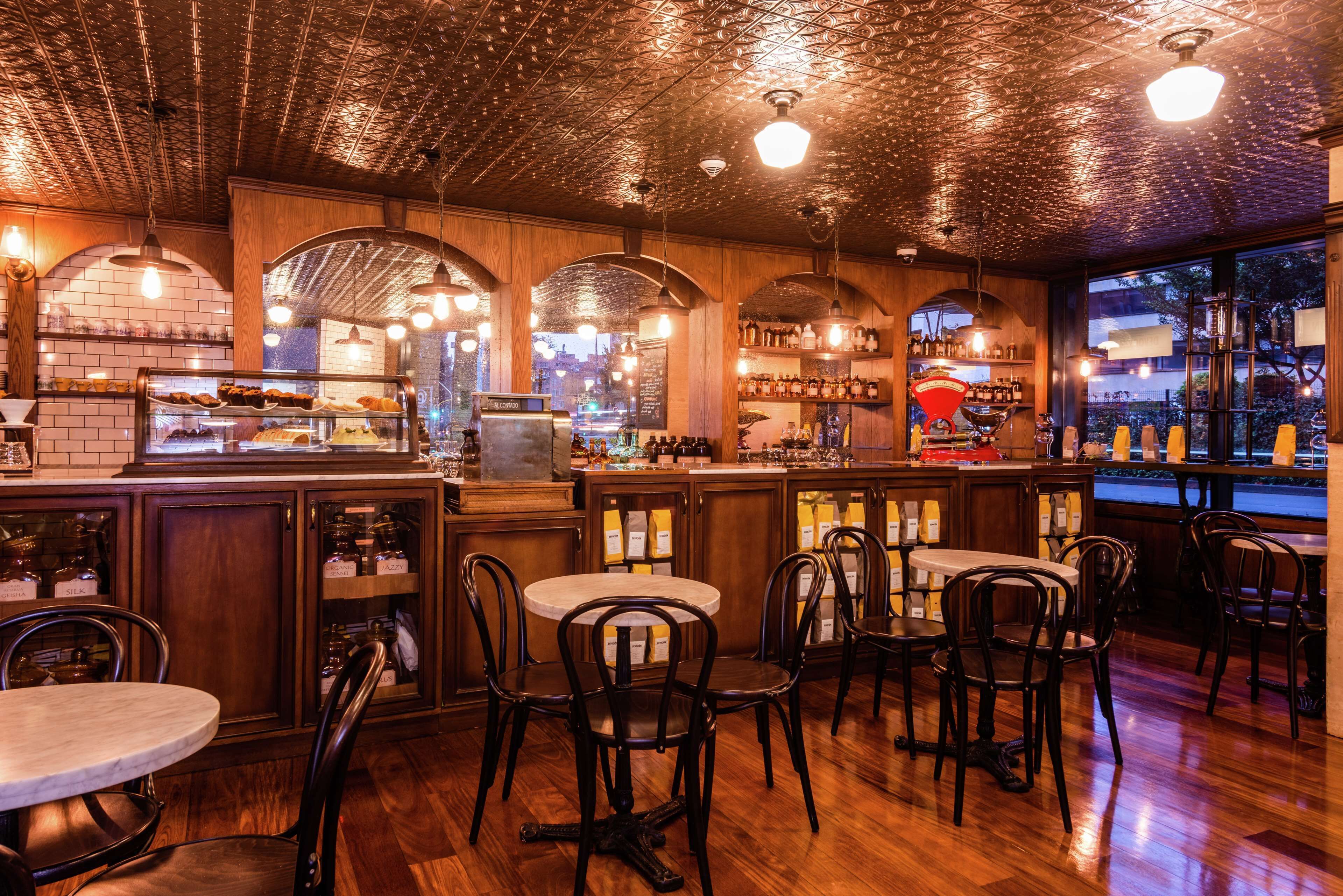 Interior de restaurante con paredes de madera, techos abovedados y una zona de bar con taburetes y botellas.