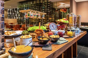 A buffet with various food items and a wine rack in the background. - Hilton Bogota (Bogotá)