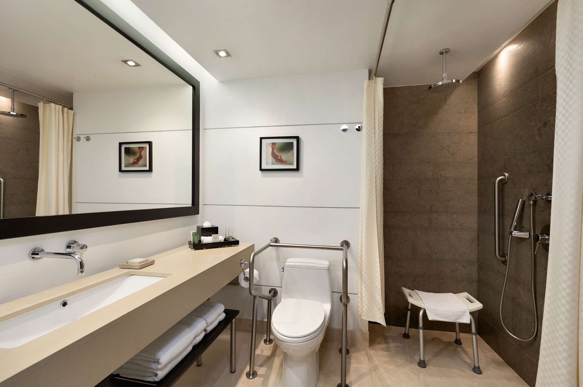 A modern bathroom with a large mirror, a sink, a toilet, and a shower area.