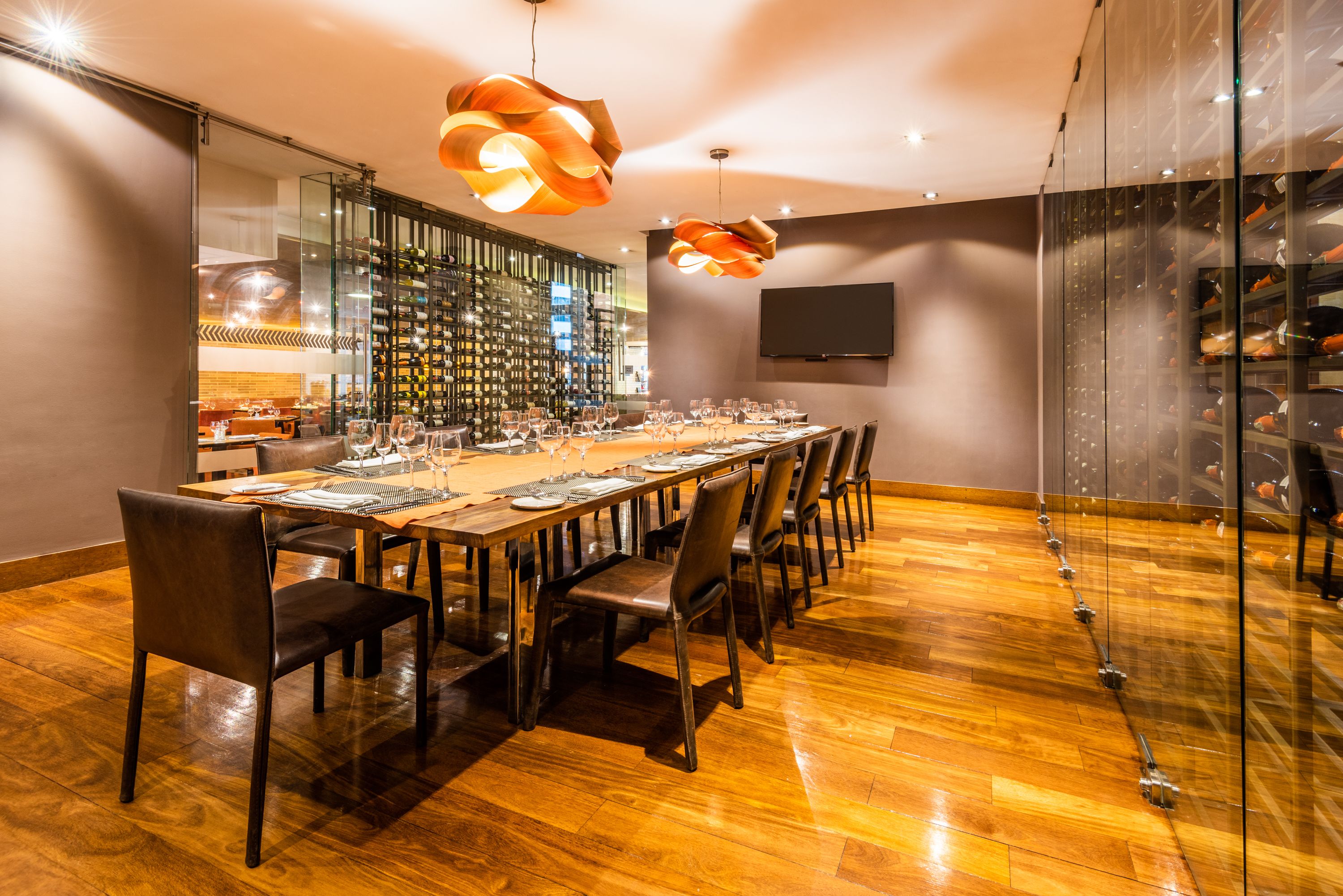 Un comedor moderno con una mesa de madera larga, múltiples sillas y lámparas colgantes.