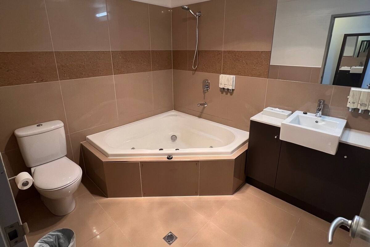 A modern bathroom with a large bathtub, a toilet, and a sink.