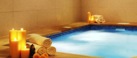 A spa area with a hot tub, candles, and towels.