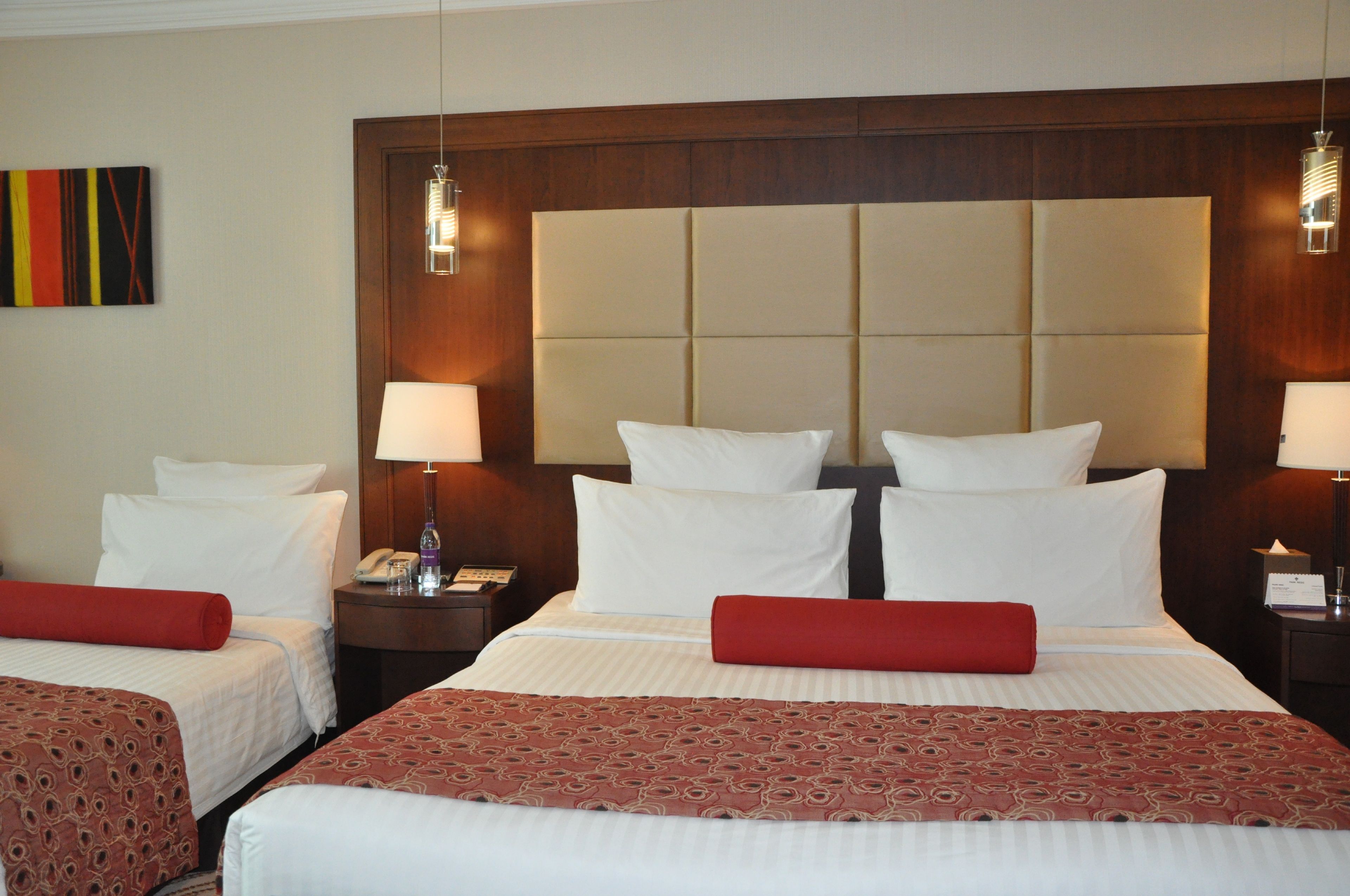 Une chambre d’hôtel avec un grand lit, deux tables de chevet, un téléphone et une lampe.