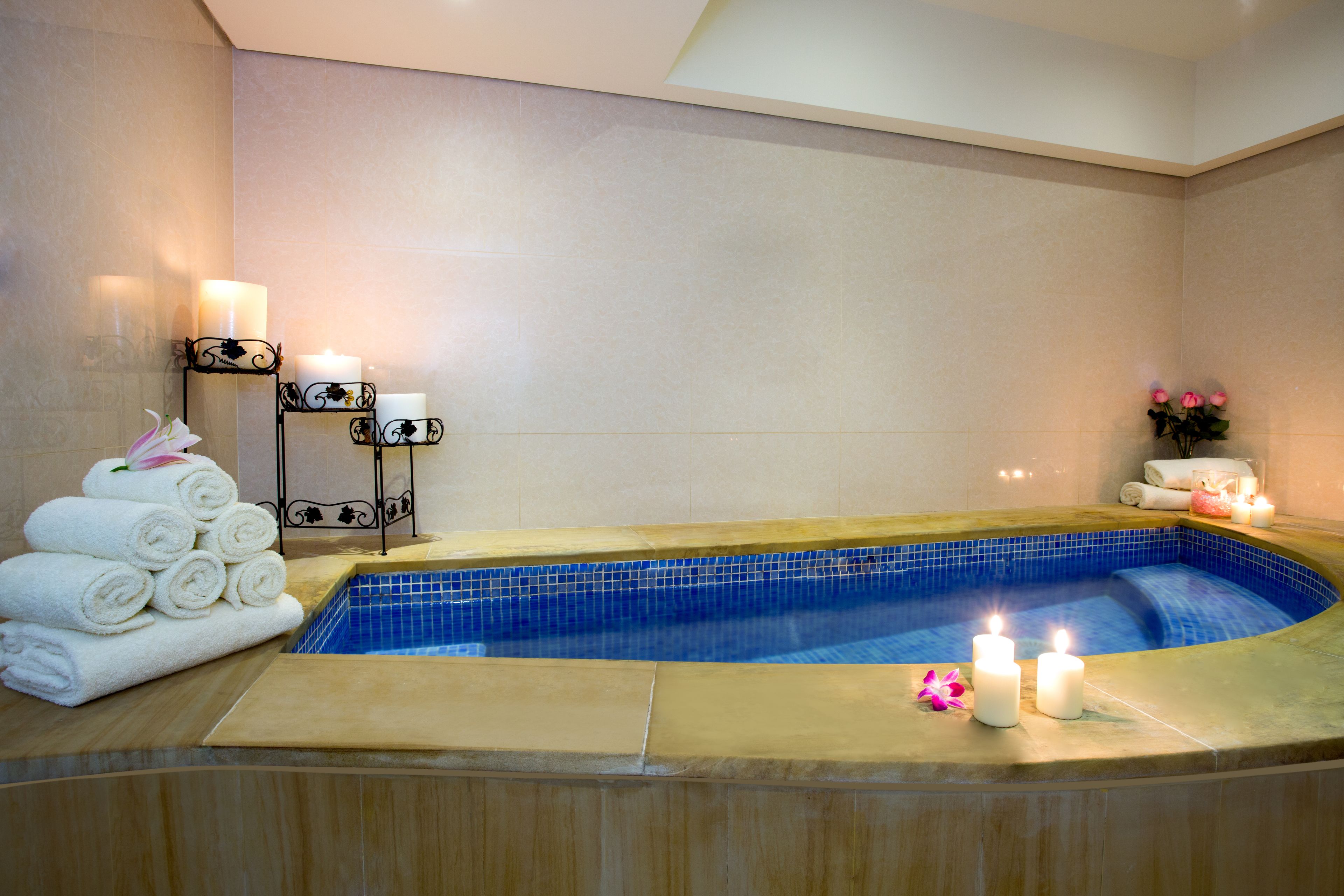 Uma área de spa com hidromassagem, toalhas, velas e um arranjo de flores.