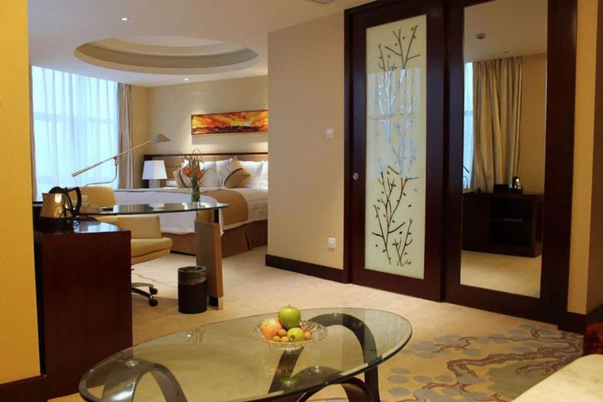 Une chambre d’hôtel avec une table en verre, un lit, un bureau et un tableau au mur.