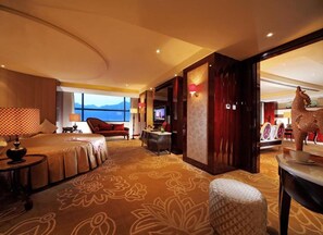 Een hotelkamer met een groot bed, een bureau, een stoel en uitzicht op de bergen.