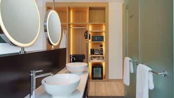 Un baño moderno con dos lavamanos grandes blancos, un espejo y una ducha a ras de suelo.