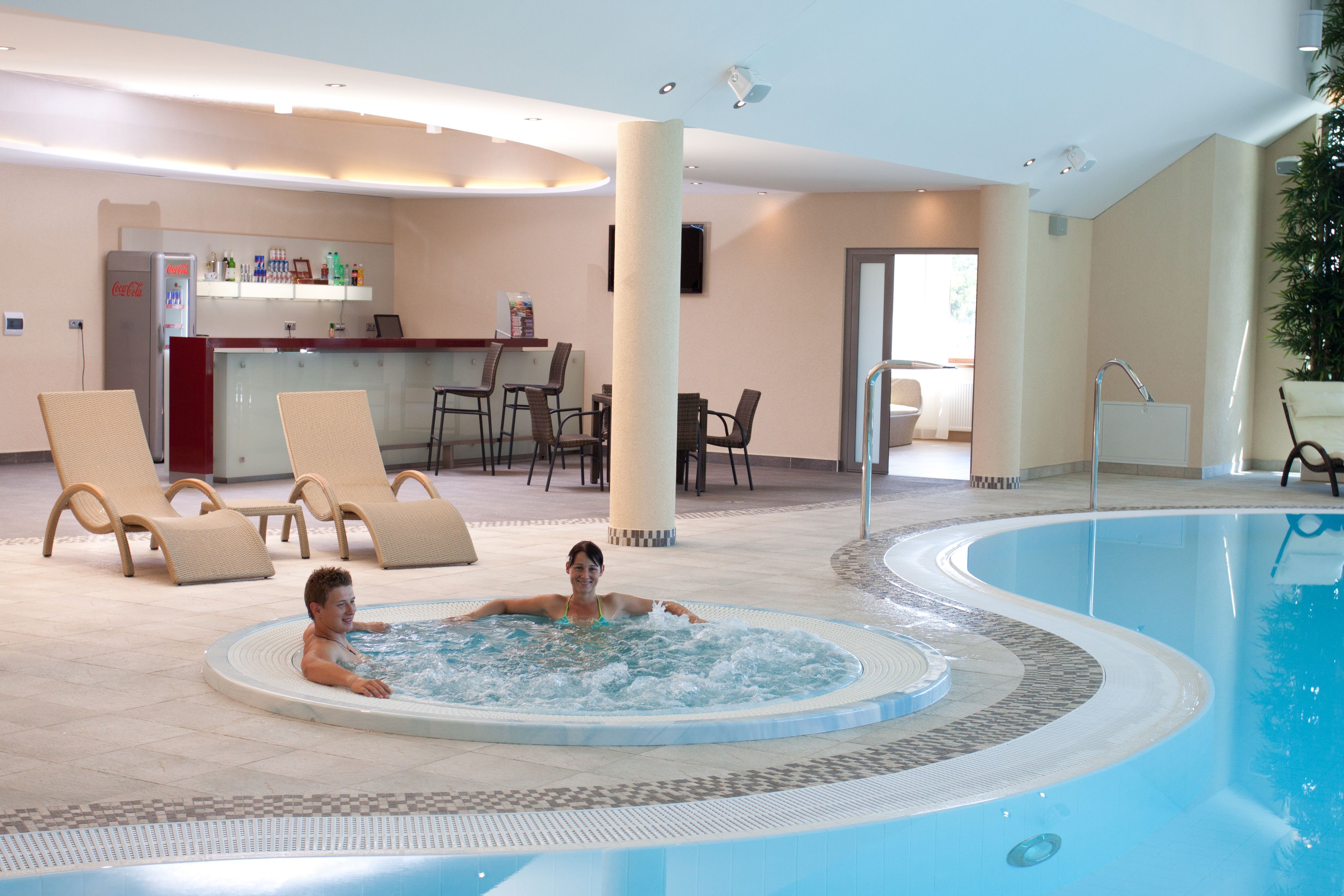 Une piscine intérieure avec des chaises longues et un espace bar.