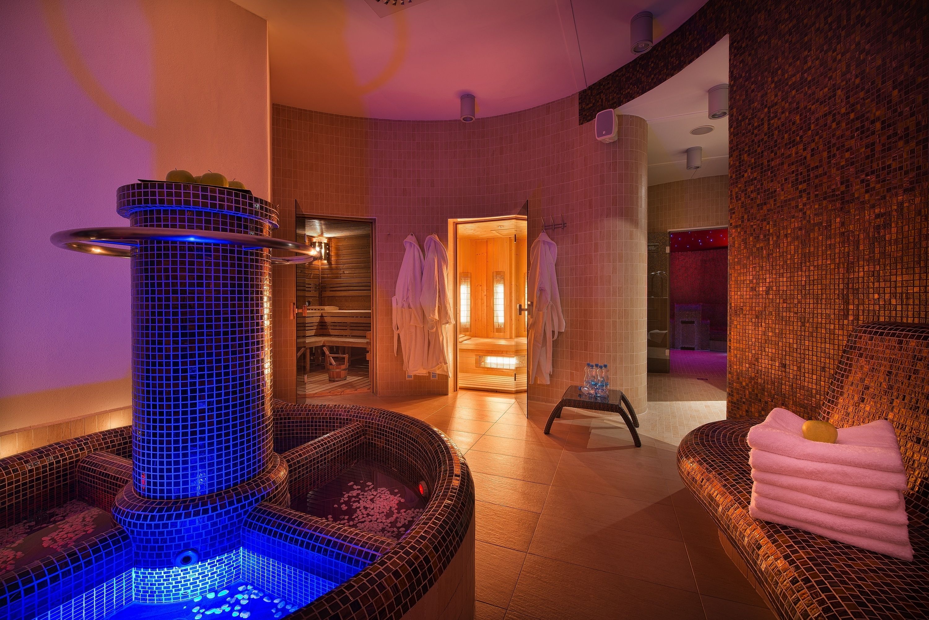 A modern spa area with a hot tub, towels, and a wooden bath area.