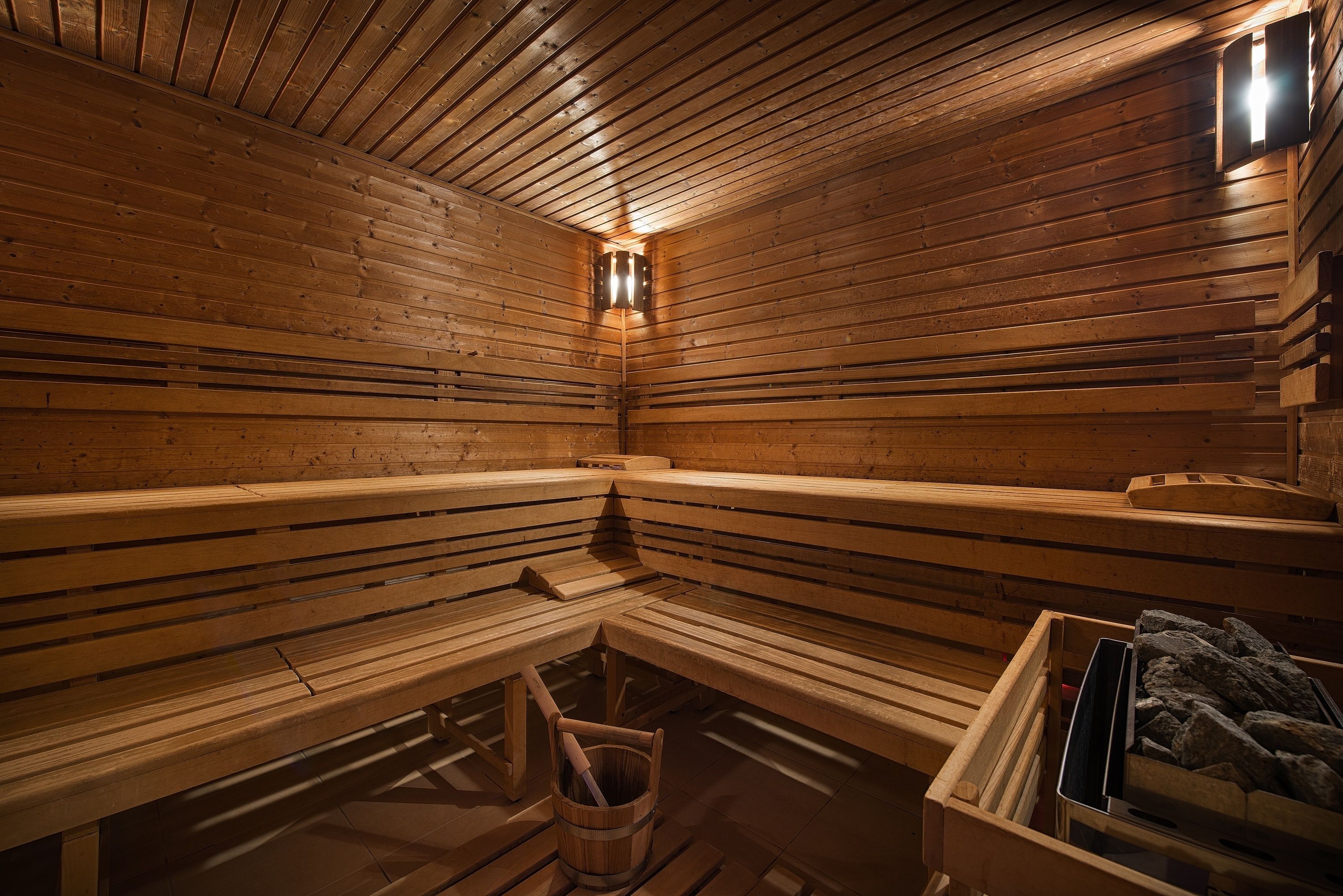 Un sauna avec des bancs en bois et un seau rempli de pierres.