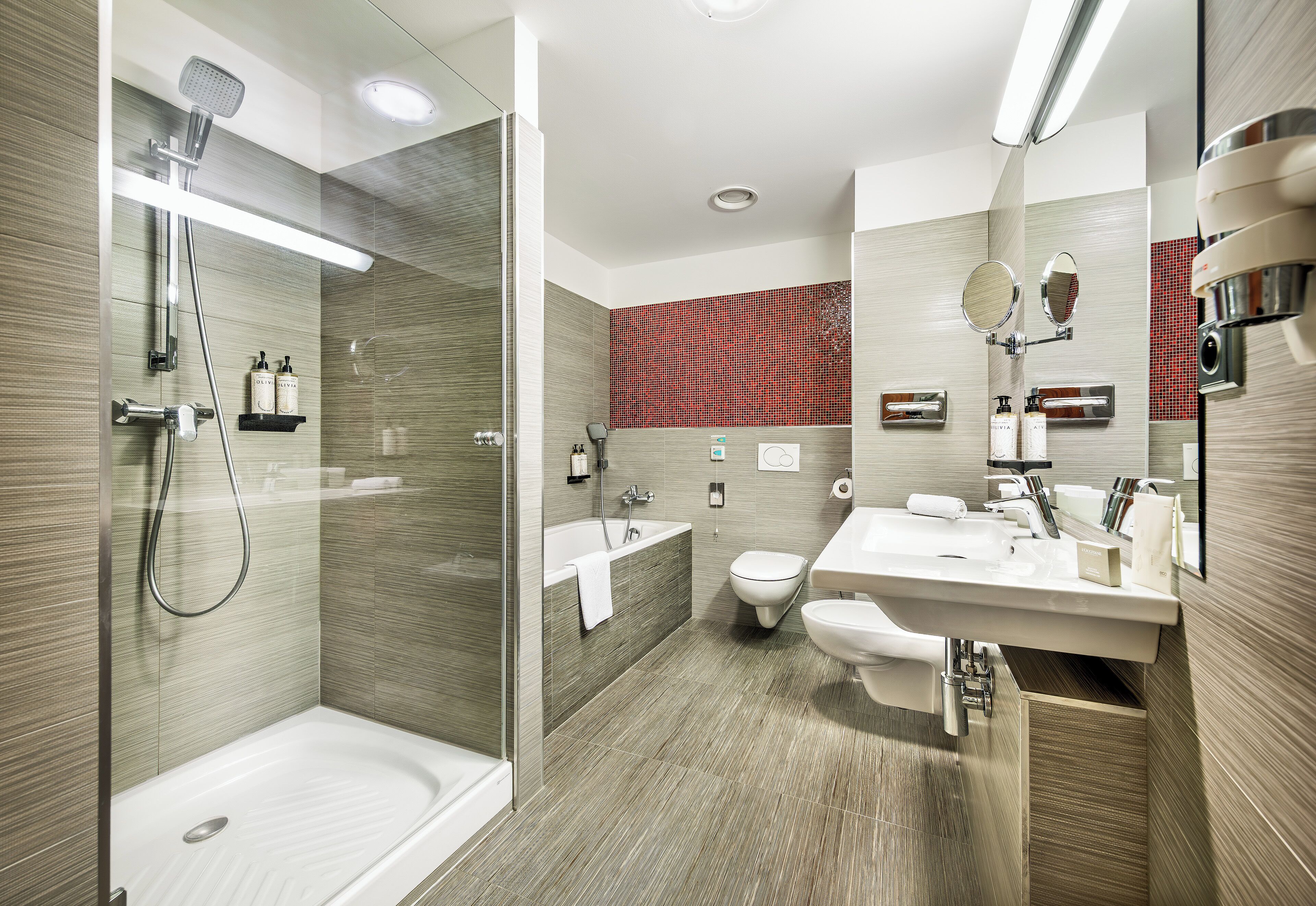 Une salle de bain moderne dotée d’une douche à parois de verre, d’une baignoire sur pieds, de toilettes et d’un meuble-lavabo avec un miroir.