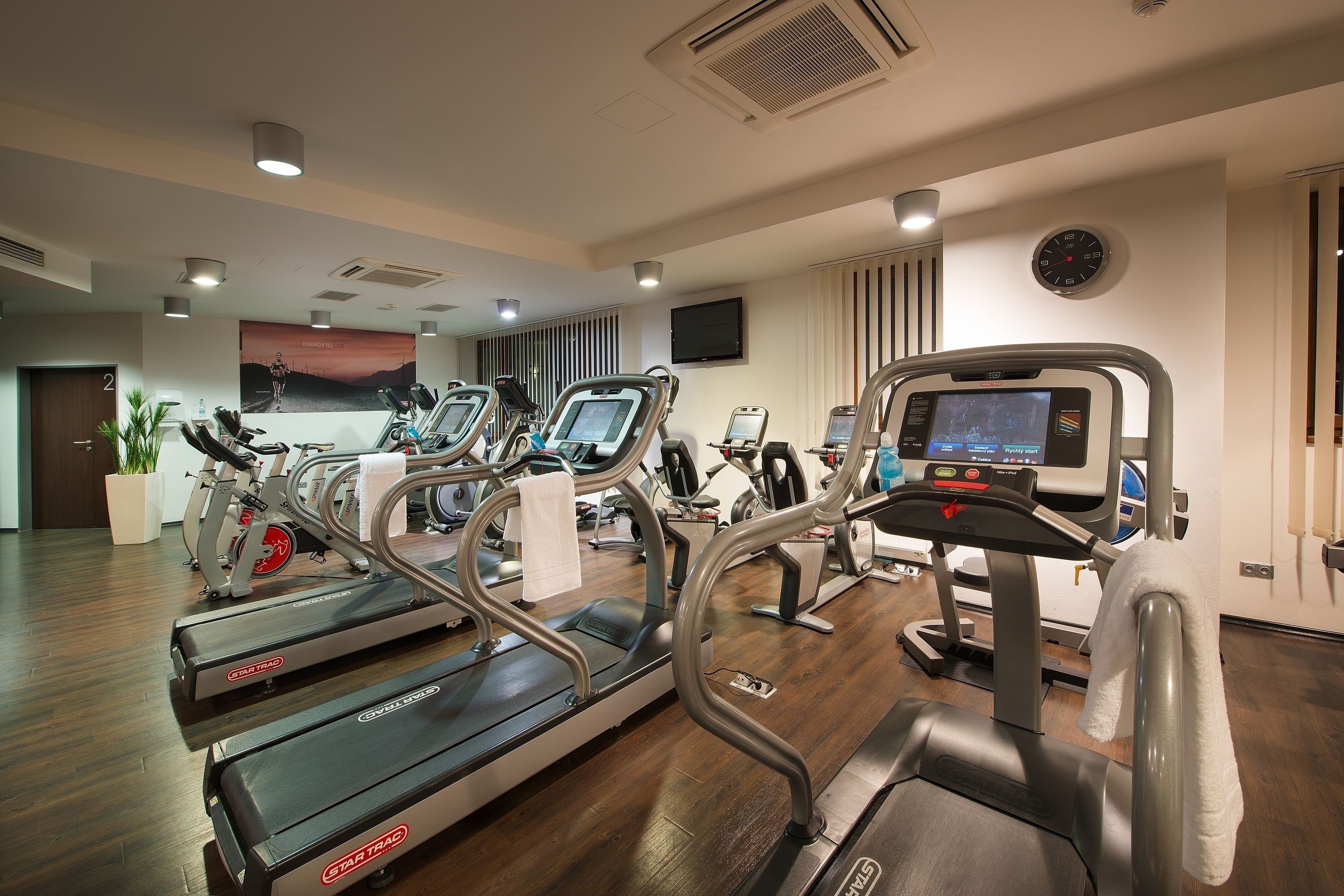 Un gimnasio con cintas de correr, bicicletas estáticas y una máquina de remo.
