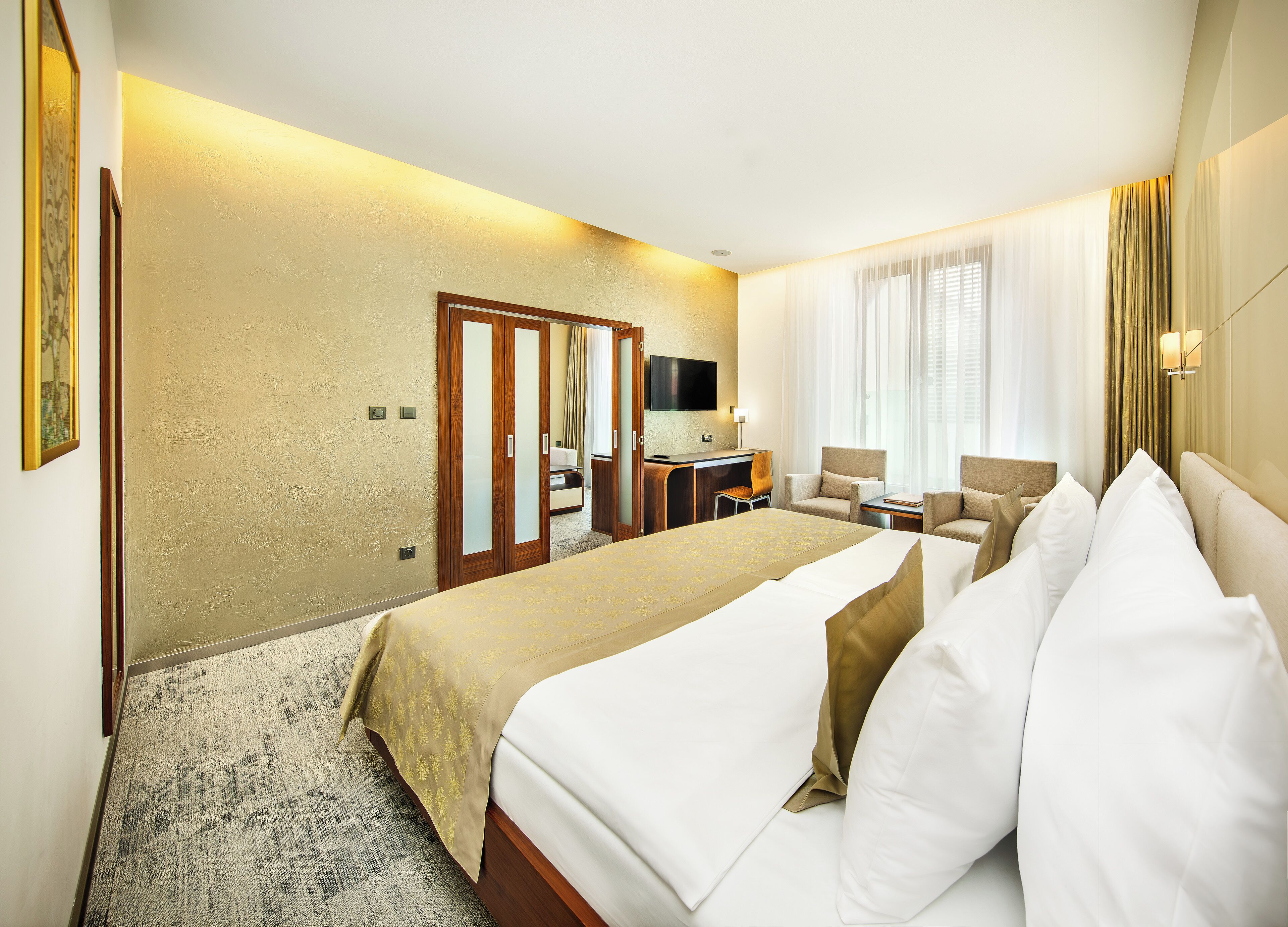 Una habitación de hotel con una cama grande, un escritorio, una silla y un televisor.