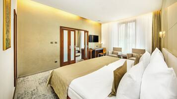 Una habitación de hotel con una cama grande, un escritorio, una silla y un televisor.