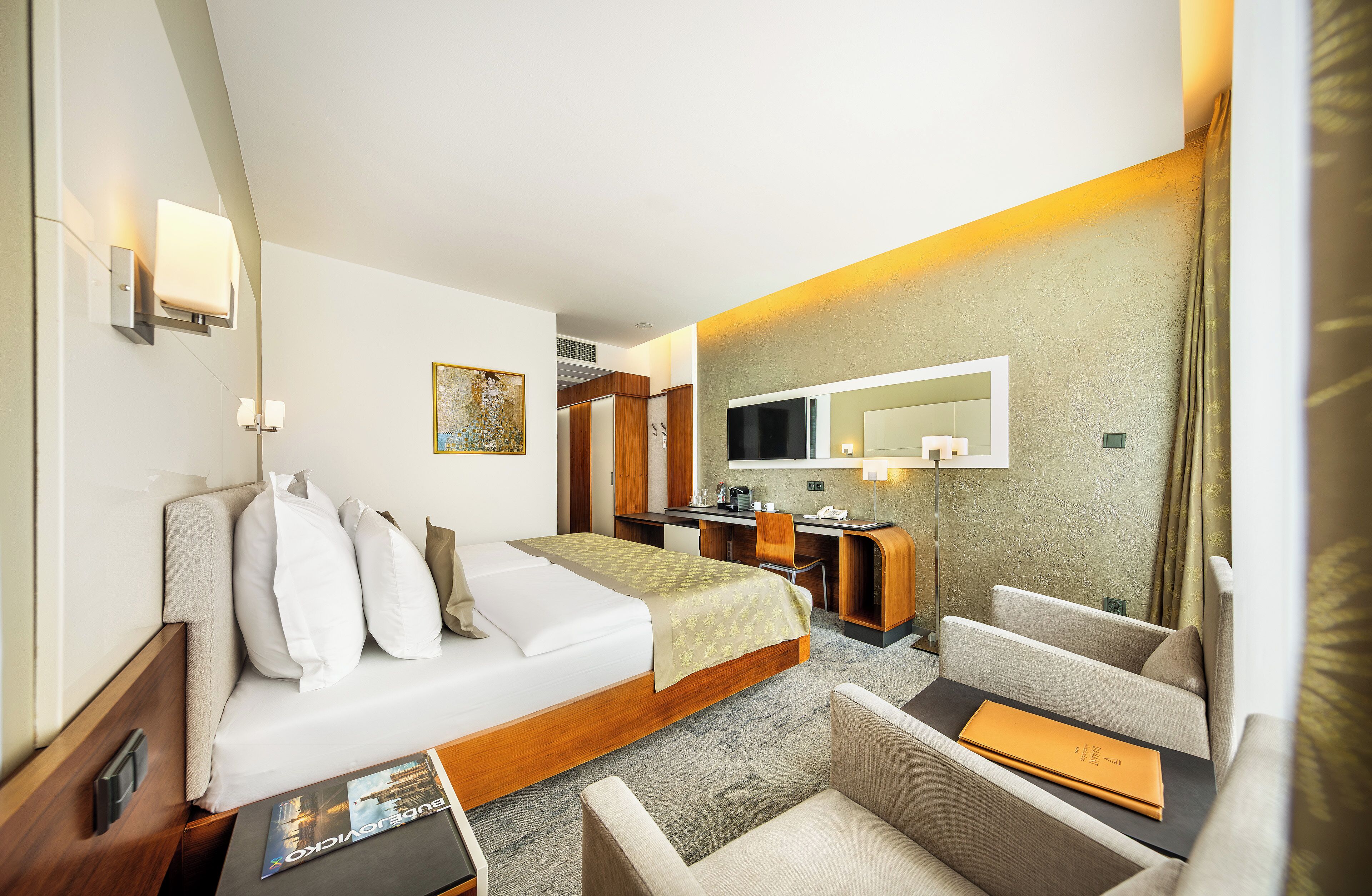 Une chambre d’hôtel équipée d’un lit, d’un bureau, d’une chaise, d’un canapé, d’une télévision et d’un miroir.