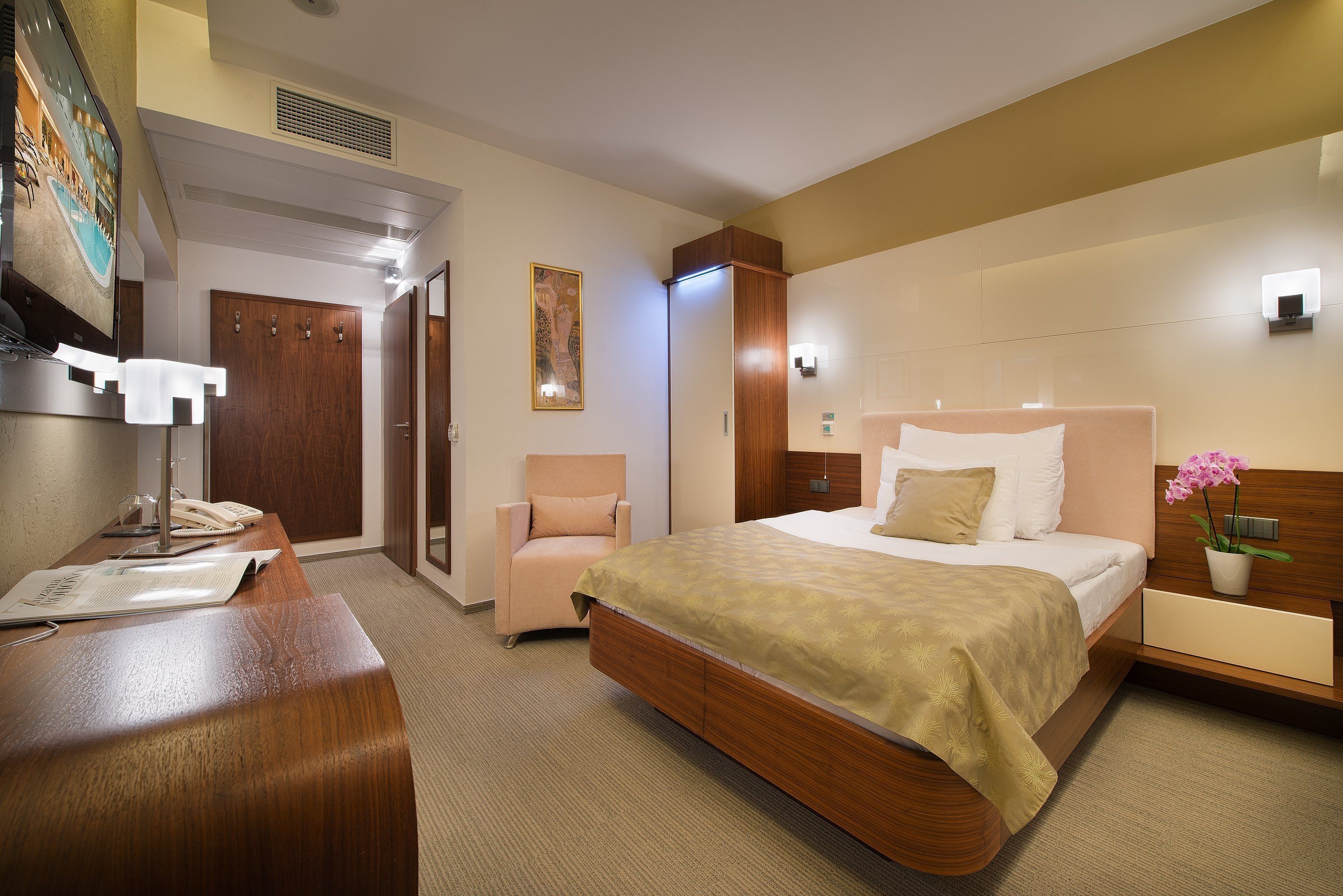 Una habitación de hotel con cama, mesita de noche, silla y escritorio con teléfono.