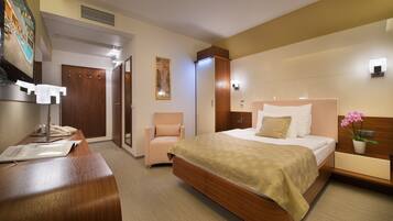 Una habitación de hotel con cama, mesita de noche, silla y escritorio con teléfono.