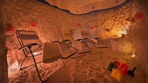 A room with stone walls, four reclining chairs, a sand floor, and a small fire feature. - Wellness Hotel Diamant (Hluboka nad Vltavou)