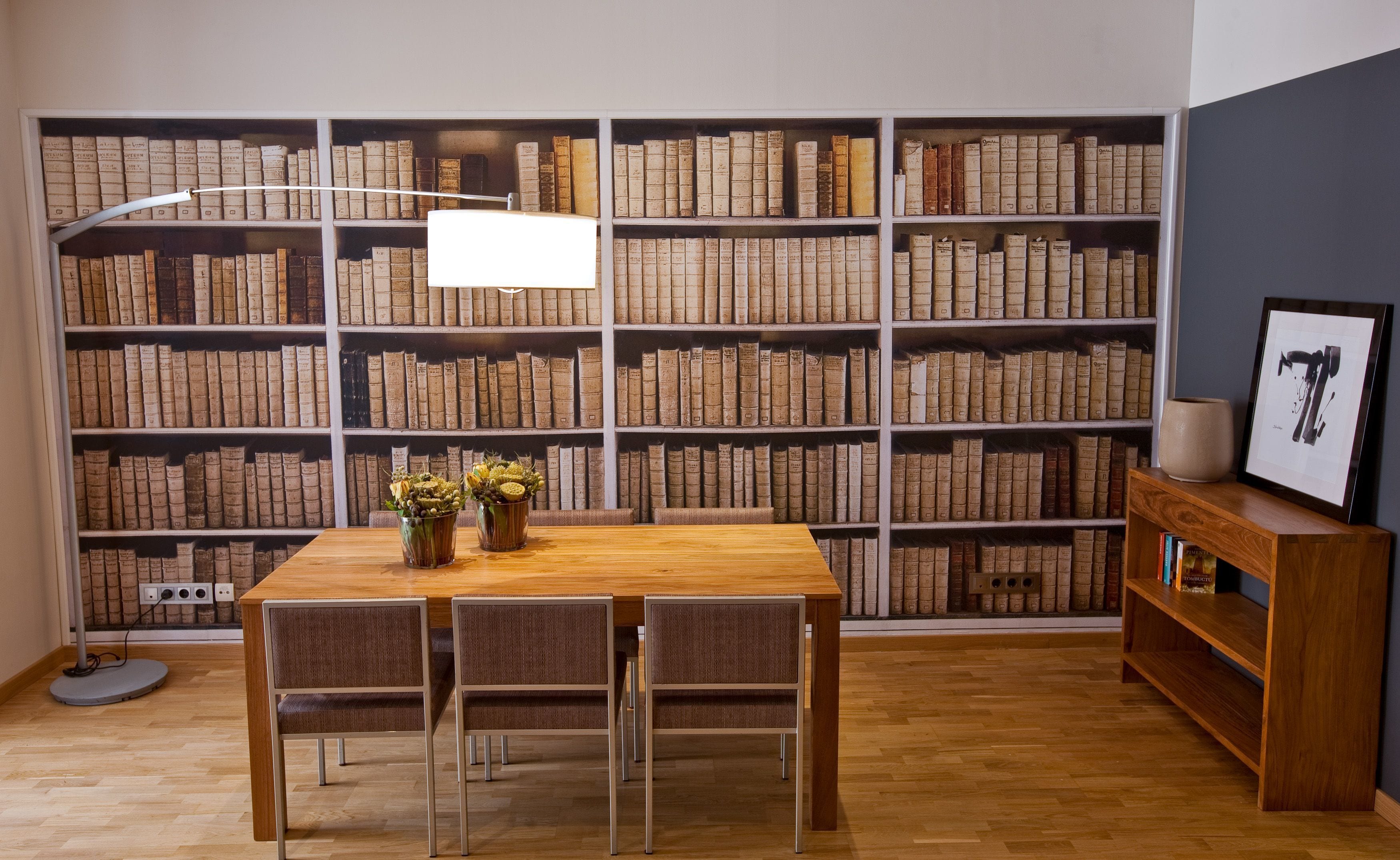 Una biblioteca con una mesa y sillas de madera, rodeada de estanterías llenas de libros.