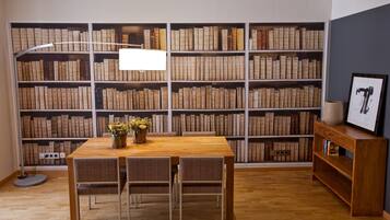 Una biblioteca con una mesa y sillas de madera, rodeada de estanterías llenas de libros.