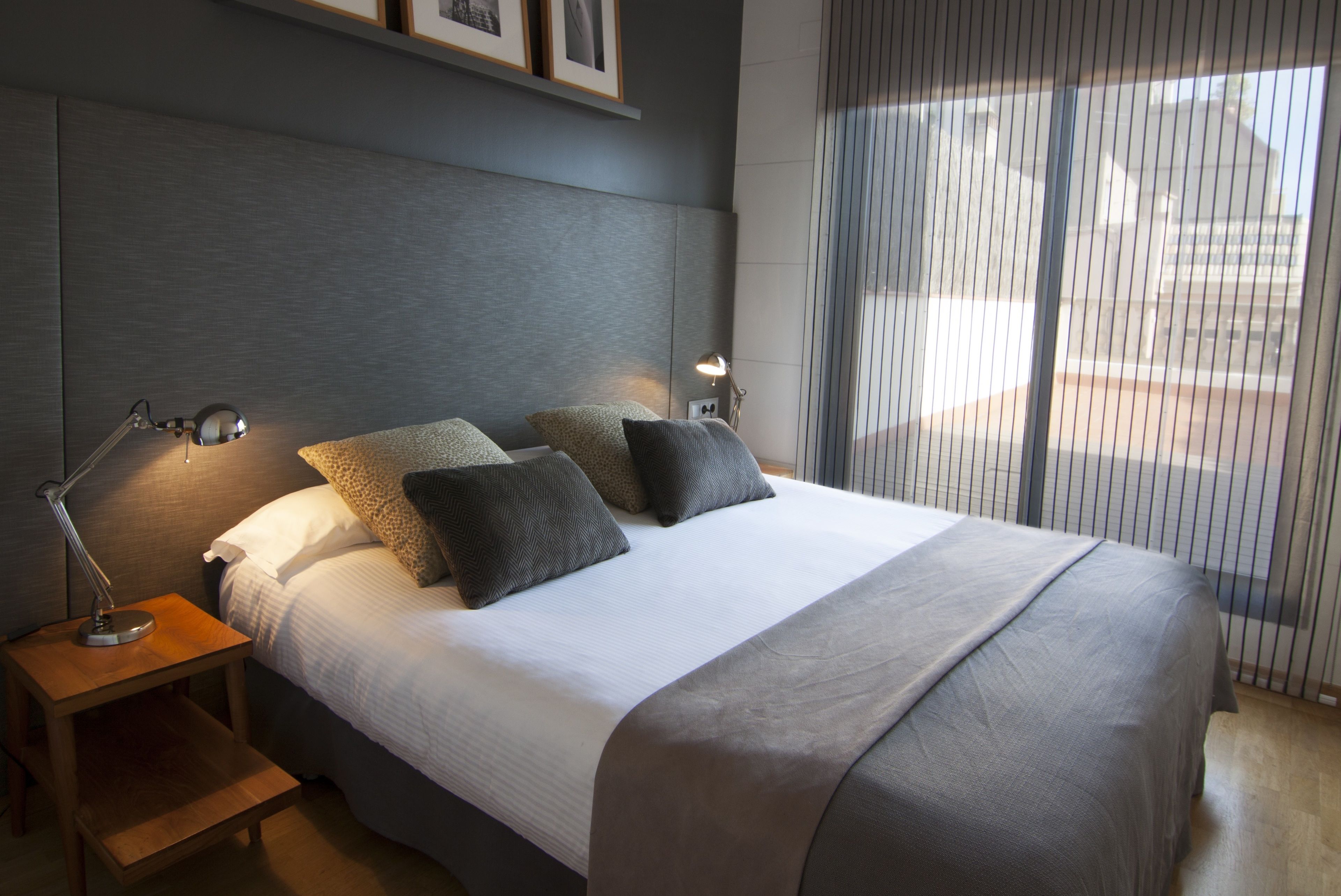 Een moderne slaapkamer met een groot bed, twee bedlampen en een uitzicht door dunne gordijnen.
