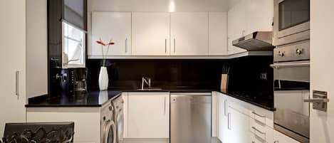 A modern kitchen with white cabinets, a dishwasher, a stove, and a coffee maker.