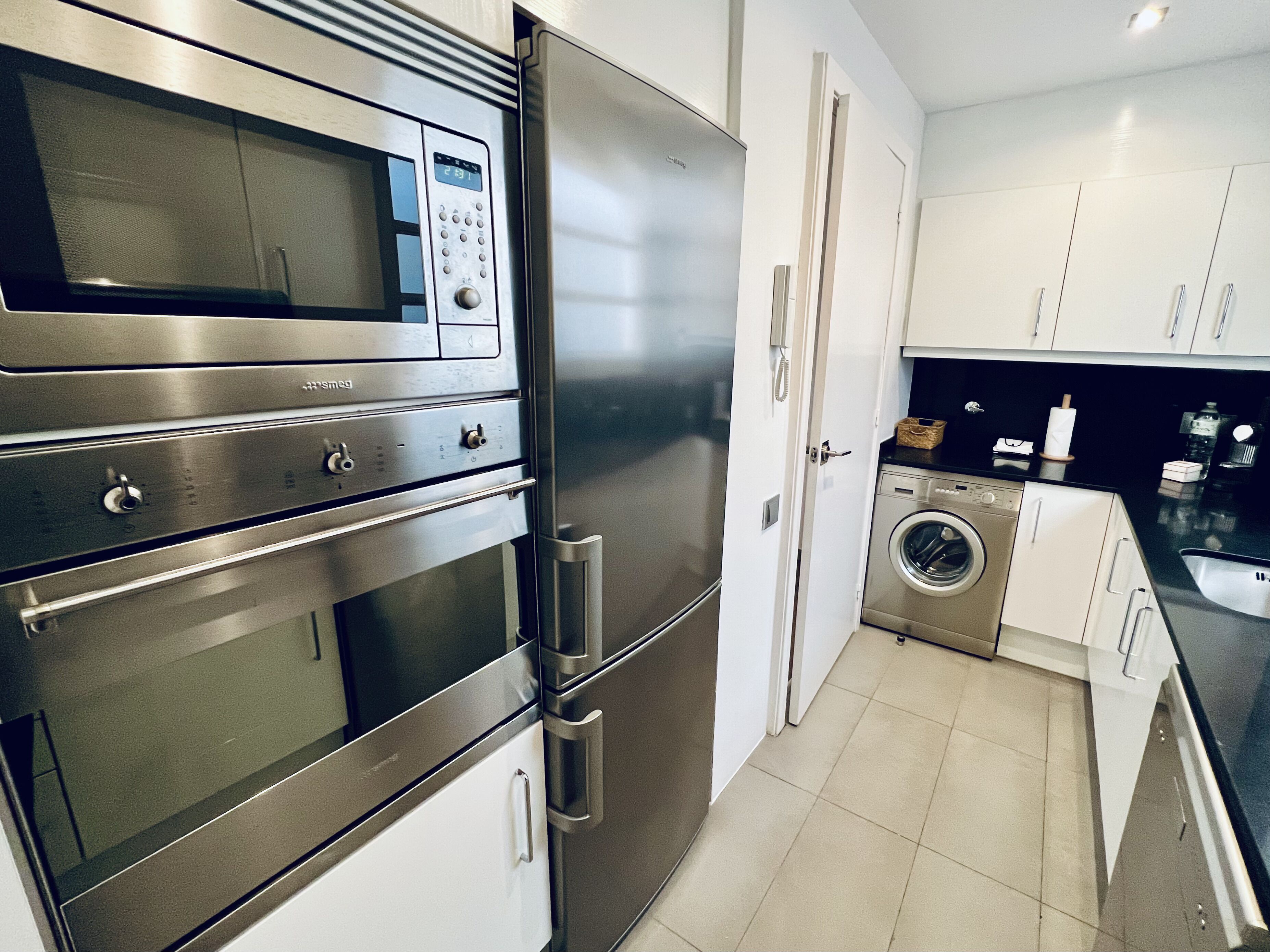 Una cocina moderna con electrodomésticos de acero inoxidable, incluyendo un microondas, horno y refrigerador.