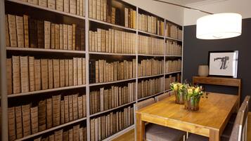 Una habitación con una mesa y sillas de madera, rodeada de altas estanterías llenas de libros.