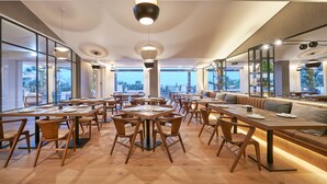 A modern dining area with tables, chairs, and a seating area with a view. - Cascade Wellness Resort Lagos Algarve by Domes (Lagos)