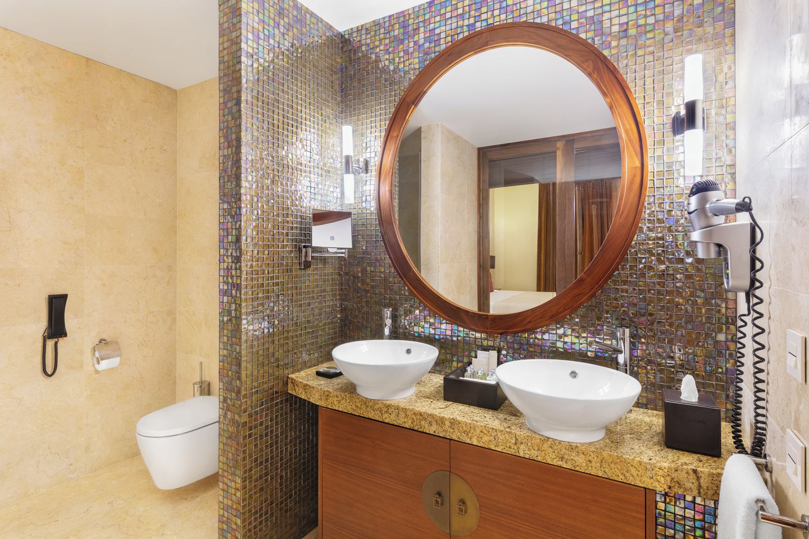 Une salle de bain avec deux lavabos, un grand miroir, un sèche-cheveux et un téléphone.