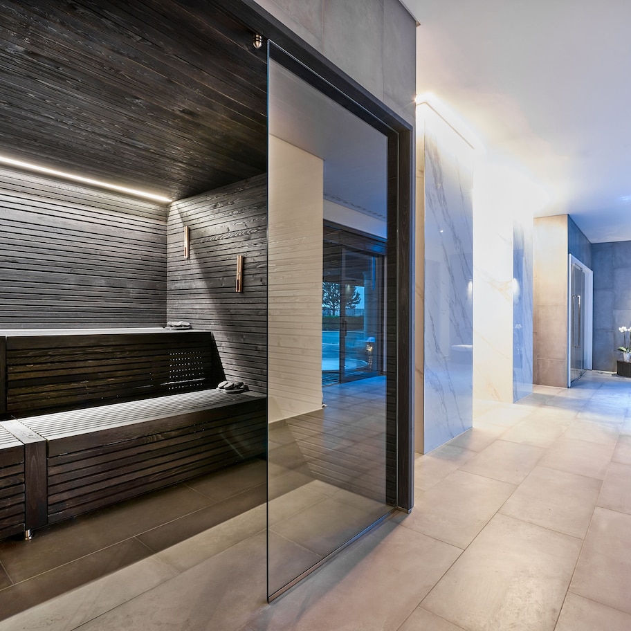 A modern bathroom with a glass partition, a bench, and a bathtub.
