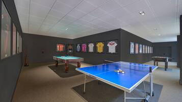 Uma sala com mesa de pingue-pongue, mesa de bilhar e snooker.