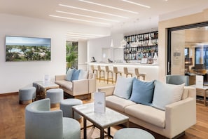 A modern lounge area with seating, a bar, and a large window with a view.