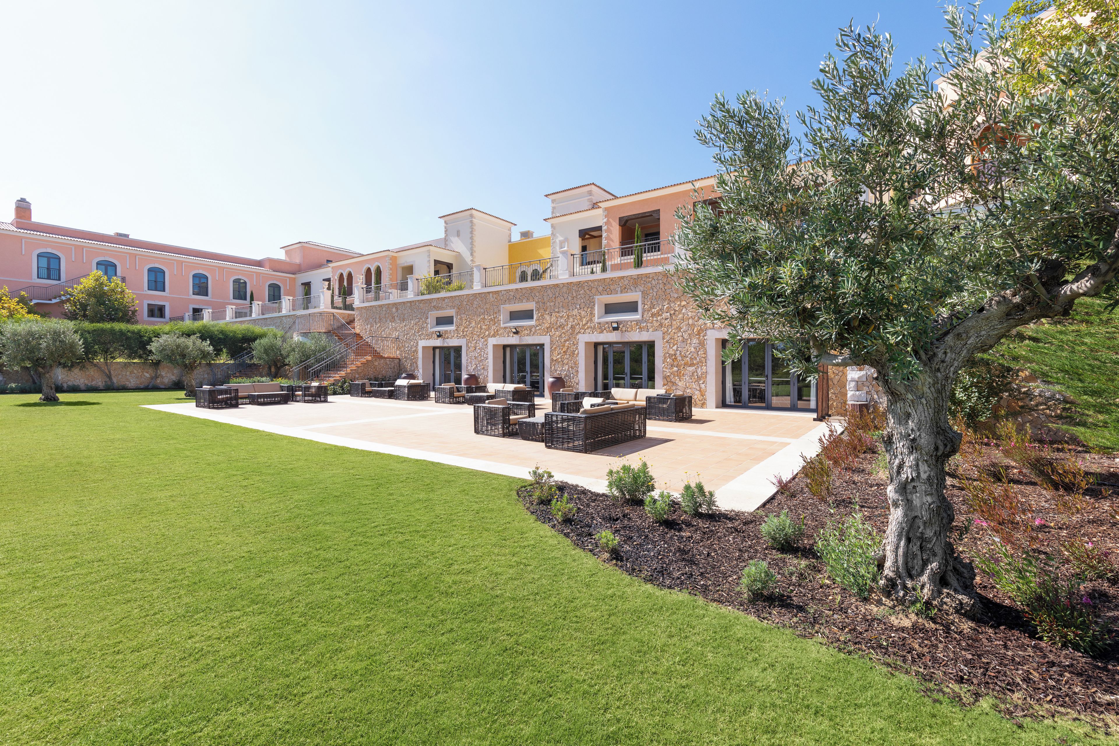 A modern building with a patio area, outdoor seating, and a well-maintained lawn.