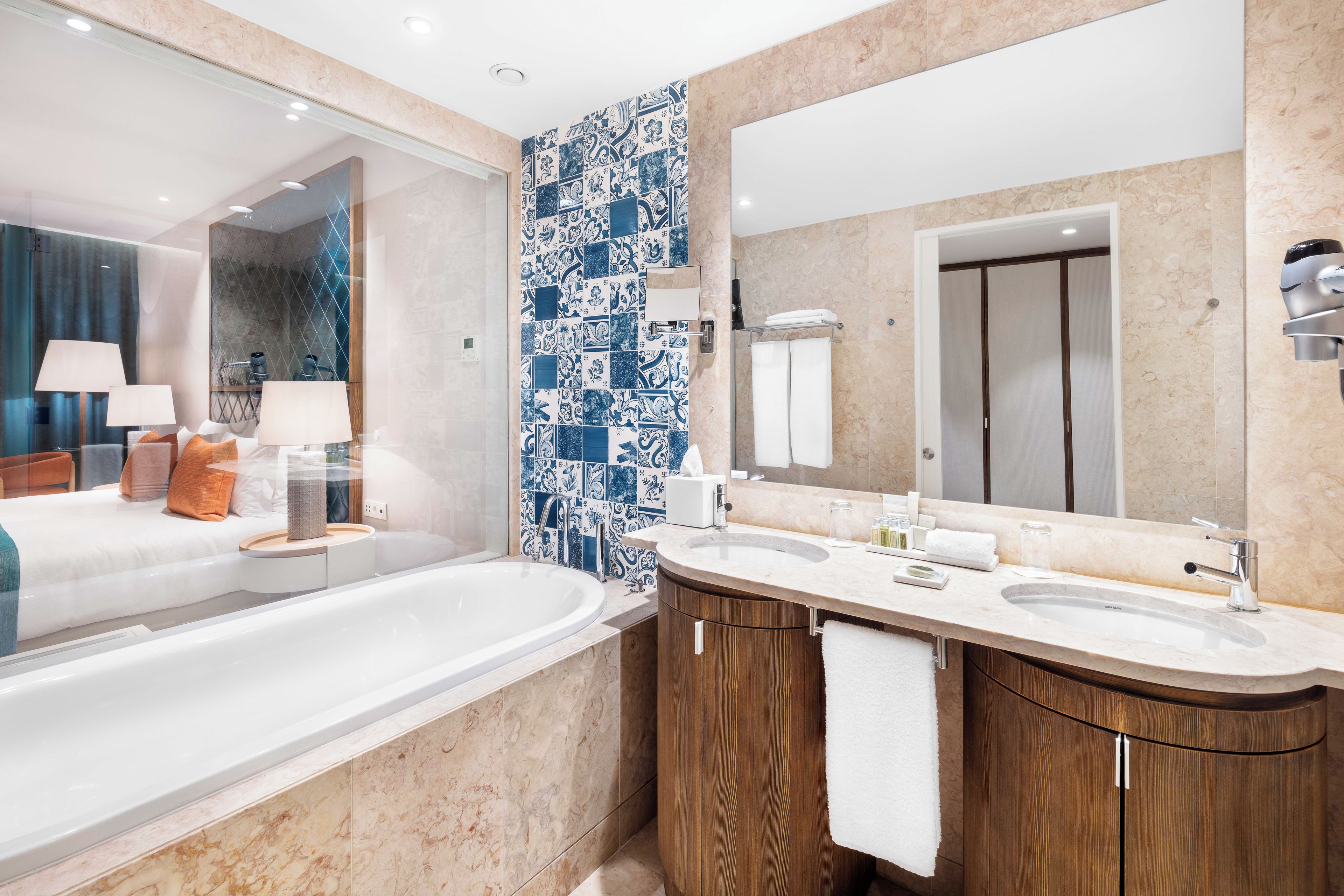 A modern bathroom with a large bathtub, two sinks, and a mirror.