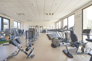 A gym with various exercise machines, a treadmill, and a weight bench.