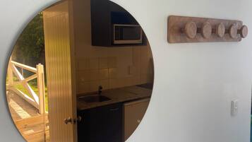 Una cocina con microondas, un fregadero y un estante de madera.