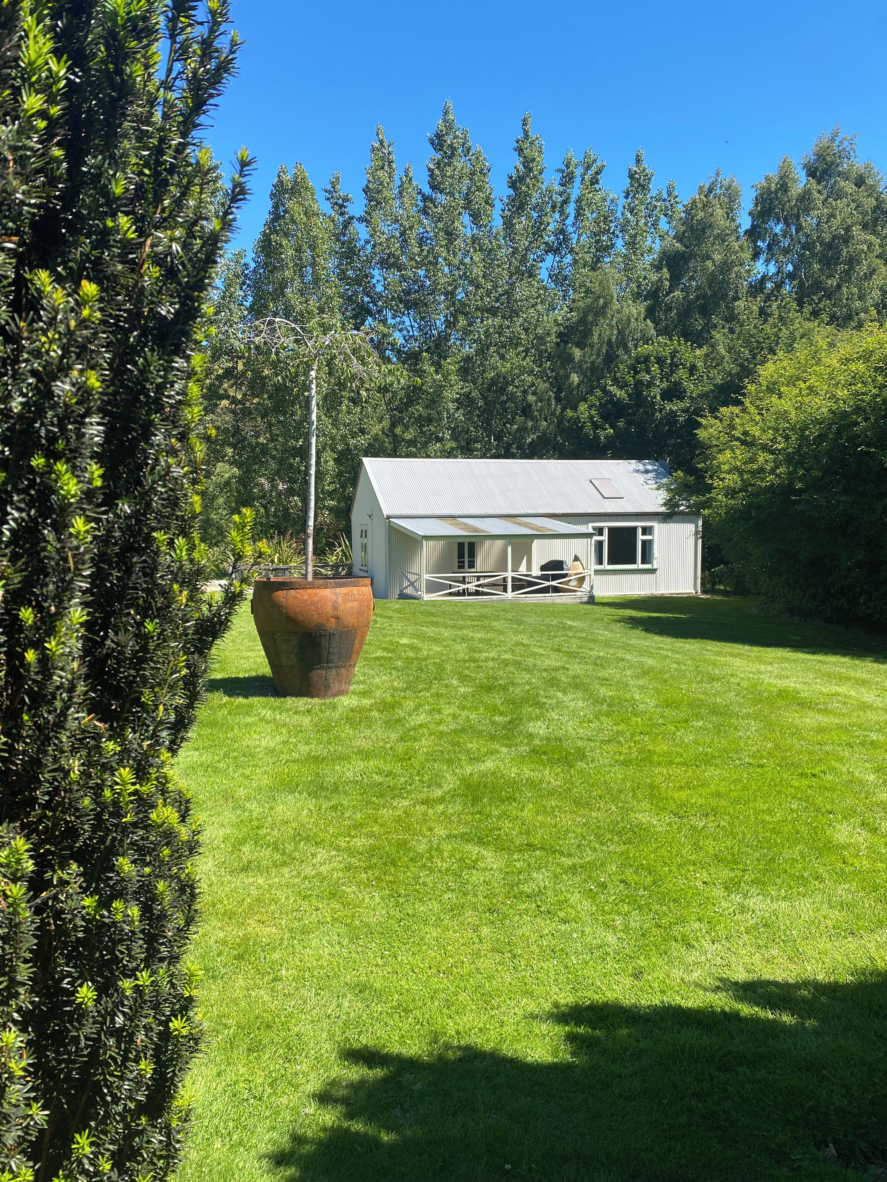 A house with a sloped roof, surrounded by a well-maintained lawn and dense trees.