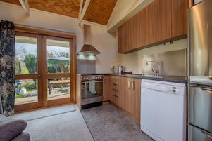 Una cocina moderna con armarios de madera, electrodomésticos de acero inoxidable y vistas a través de un ventanal.