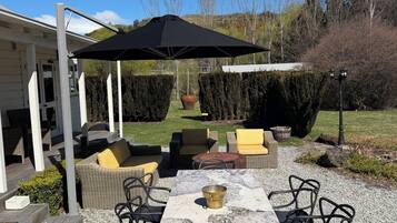 An outdoor patio with a table, chairs, and a pergola with a black umbrella.