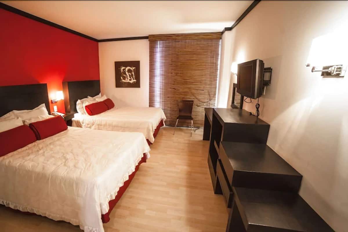Habitación de hotel con dos camas, televisión y escritorio.
