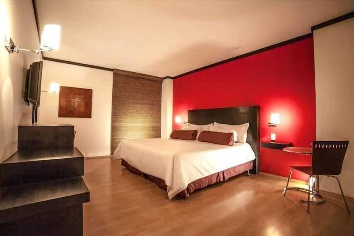 Una habitación de hotel con una cama, una silla, un escritorio y una escalera.